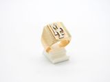 un gros plan d'une bague en or sur laquelle figure la lettre « m »