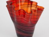 un vase en verre rouge et noir posé sur une surface blanche
