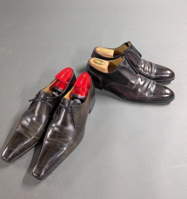 pair of men ' s black leather shoes with red soles on a grey surface