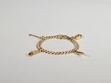 gros plan d'un bracelet en or sur une surface blanche
