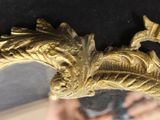 a mirror with a gold bird on it and a person taking a picture in the mirror