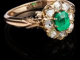 un gros plan d'une bague en or sertie d'une émeraude verte et de diamants blancs