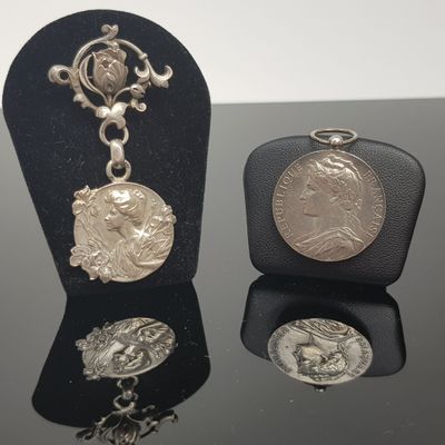 deux pièces d'argent et un collier exposés sur un fond noir