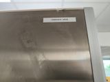 a stainless steel refrigerator with a sign on the door