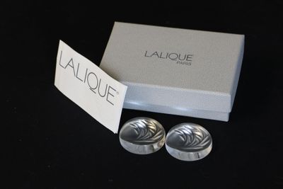 deux paires de menottes en argent, présentées dans une boîte blanche posée sur un fond noir