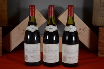 three bottles of red wine sit on a red table cloth