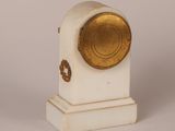 a white and gold clock on a white pedestal
