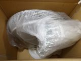 a white toilet in a box with a plastic cover on it