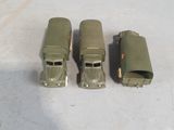 three toy army vehicles are lined up on a white surface
