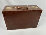 an old brown suitcase sitting on top of a white surface
