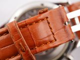 a close up of a watch with a brown leather strap