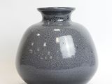 a gray vase sitting on a white surface with a white background