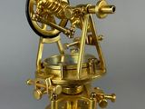 an antique brass telescope on a tripod stand against a gray background