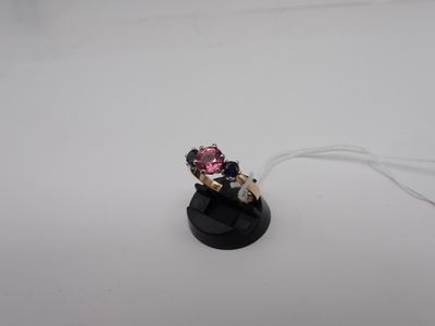 une petite bague rose et blanche posée sur un socle noir