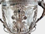 a silver vase with a bird on top of it