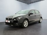 La voiture grise est garée dans une grande pièce au sol noir.