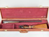 a wooden case with a rifle in it on a white surface