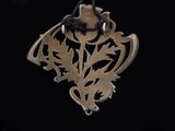 silver pendant with a dragon and a hat on it on a black background
