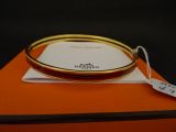 une boîte orange sur laquelle est posé un bracelet rigide doré