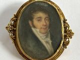 un portrait ancien représentant un homme en costume et cravate, dans un cadre doré