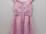 a pink dress hanging on a hanger against a white wall