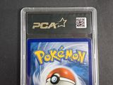 the pokemon card is in a plastic case on a table