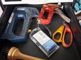 a drawer with tools in it and a person ' s hand holding a tool
