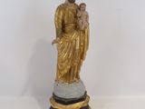 une statue de Jésus tenant un enfant dans ses bras, posée sur un socle
