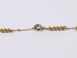 a close up of a gold beaded bracelet on a white background