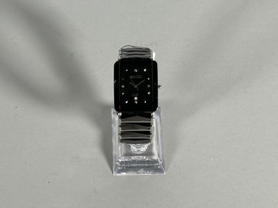 a watch sitting on a clear stand on a white surface