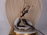 une statue représentant une femme tenant un éventail, posée sur une table