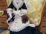 a doll that is sitting on a chair with a teddy bear