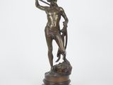 une statue en bronze représentant un homme tenant une épée, posée sur un socle en bois