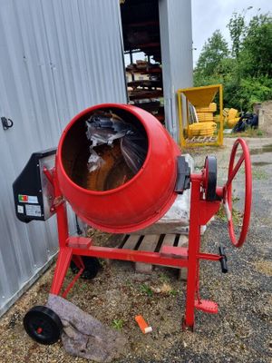 une bétonnière rouge garée devant un immeuble