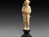 une figurine en ivoire sculpté représentant un homme tenant un panier