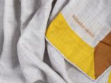 a close up of a yellow and grey scarf on a bed