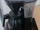 a black coffee maker on a wooden table in a kitchen