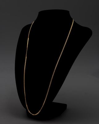 un collier à chaîne en or posé sur un présentoir noir pour mannequin
