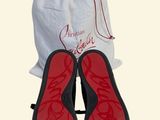 pair of black and red slippers with red soles next to a white bag
