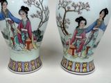 pair of vases with asian women on them on a white surface
