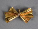a gold bow brooch with a diamond in it