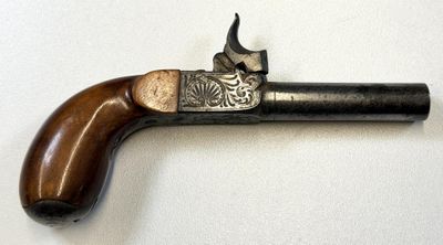 un vieux pistolet avec une poignée en bois sur une surface blanche