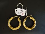 deux boucles d'oreilles en anneau dorées avec une étiquette de prix sur fond noir