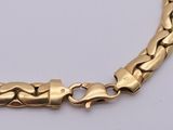 a close up of a gold chain bracelet on a white surface