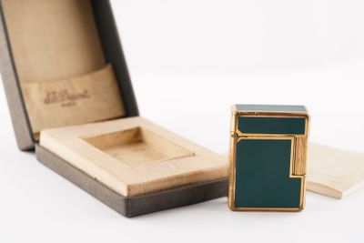 a green lighter sitting in a box next to a piece of paper