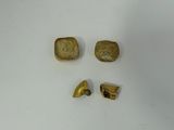 three pieces of gold are shown on a white surface