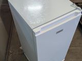 a small white refrigerator sitting on the floor in a room
