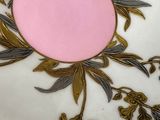a white plate with gold and pink decoration on it