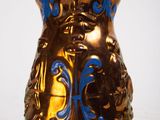 a gold vase with blue designs on it on a white surface
