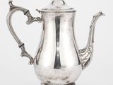 une cafetière en argent munie d'une anse et posée sur un socle